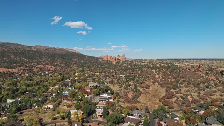 Ripresa aerea panoramica in dolly che si eleva sopra un quartiere verso il Garden of the Gods, Colorado, durante l'autunno