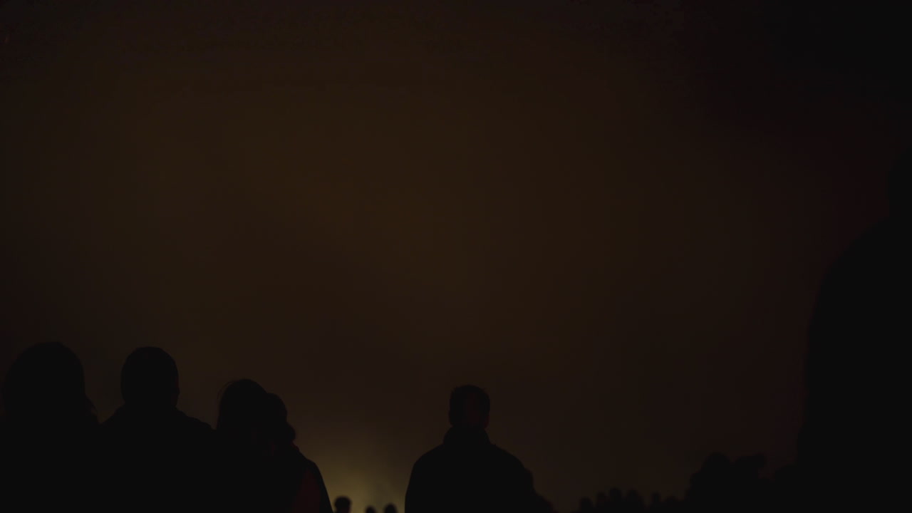 폭발하는 불꽃 놀이는 밝은 로켓과 매혹적인 불꽃 놀이의 빛을 반사하여 번쩍이는 연기 베일을 만듭니다.