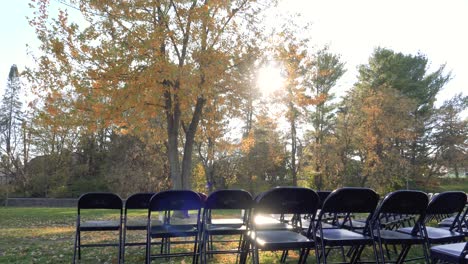 autumn sunset in colorful city park, recreational folding chairs under a large tree