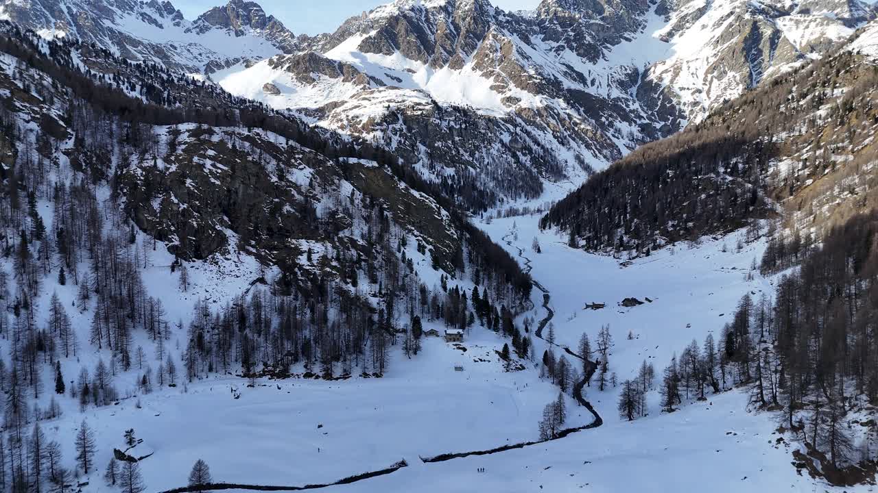 Beautiful drone footage of a snowy slope with majestic mountains in the background, in the Italian Alps (Aosta Valley). [Drone movement: revealing + pitch forward]