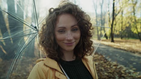 portrait of ginger caucasian woman with transparent umbrella in the park.