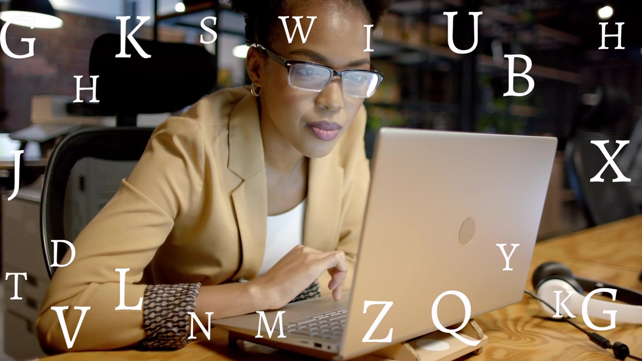 Woman typing and pausing at office desk, causing animated letters overlay laptop for business focus
