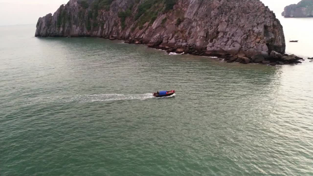 Small fishing boat moving forward in big sea in tropical landscape