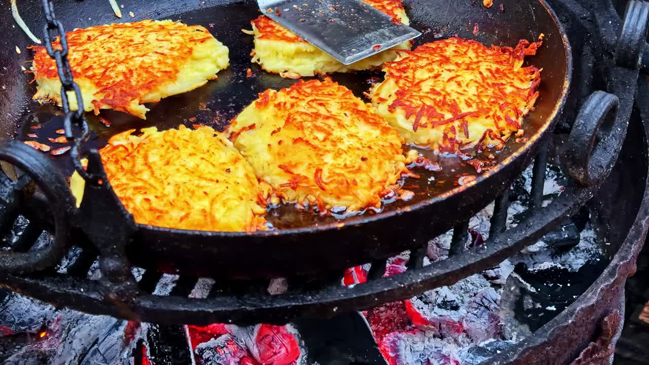 Nærbillede af stegepande med kroketter, der tilberedes i varm olie over trækul, slowmotion.