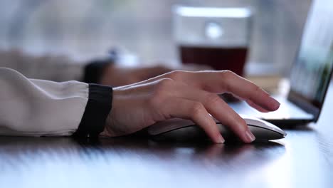 a profile shot of a woman's hand on a magic mouse, scrolling and selecting a file