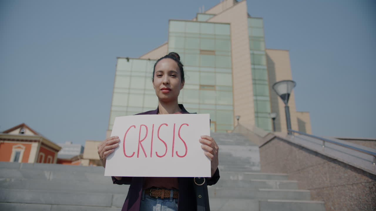 Woman holding a sign reading "Crisis" in a public space