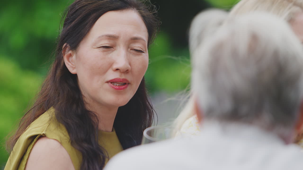 성숙 한 친구 들 이 집 의 정원 에서 여름 의 술 파티 에서 와인 을 마시고 이야기 하고 있다