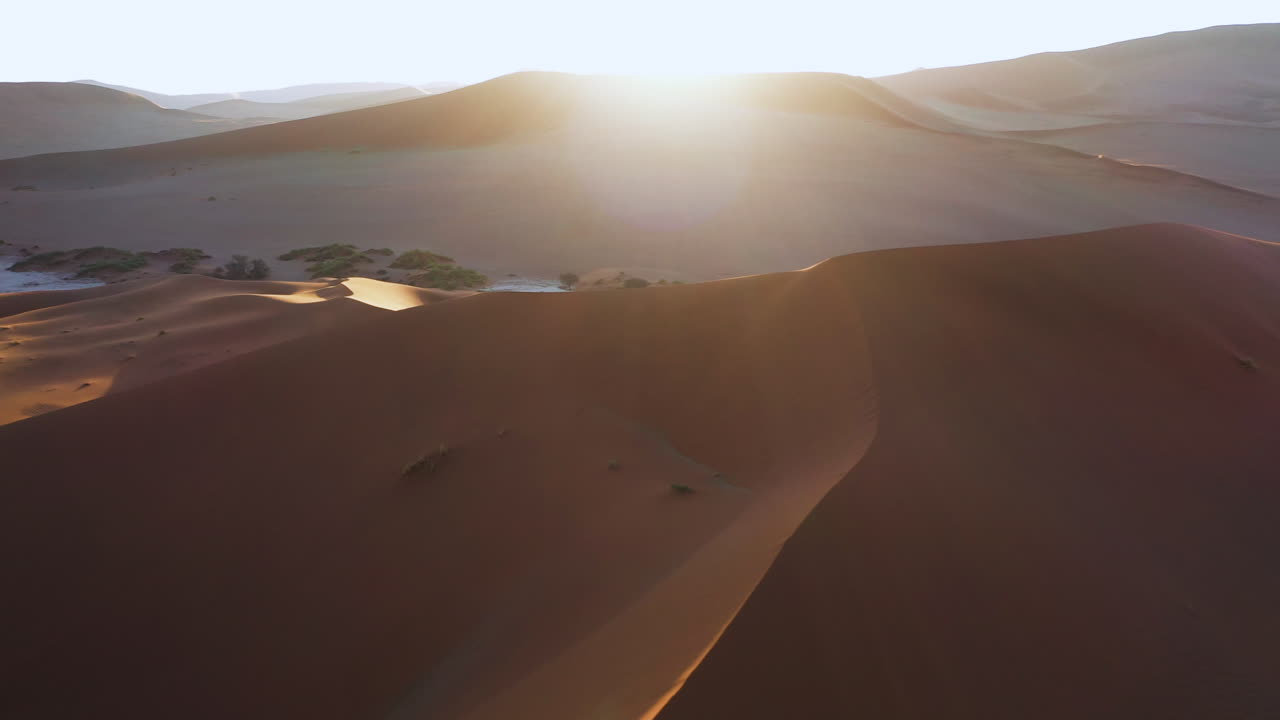 Drone shot panning over sunlit sand dunes in the Namib desert, sunset in Namibia