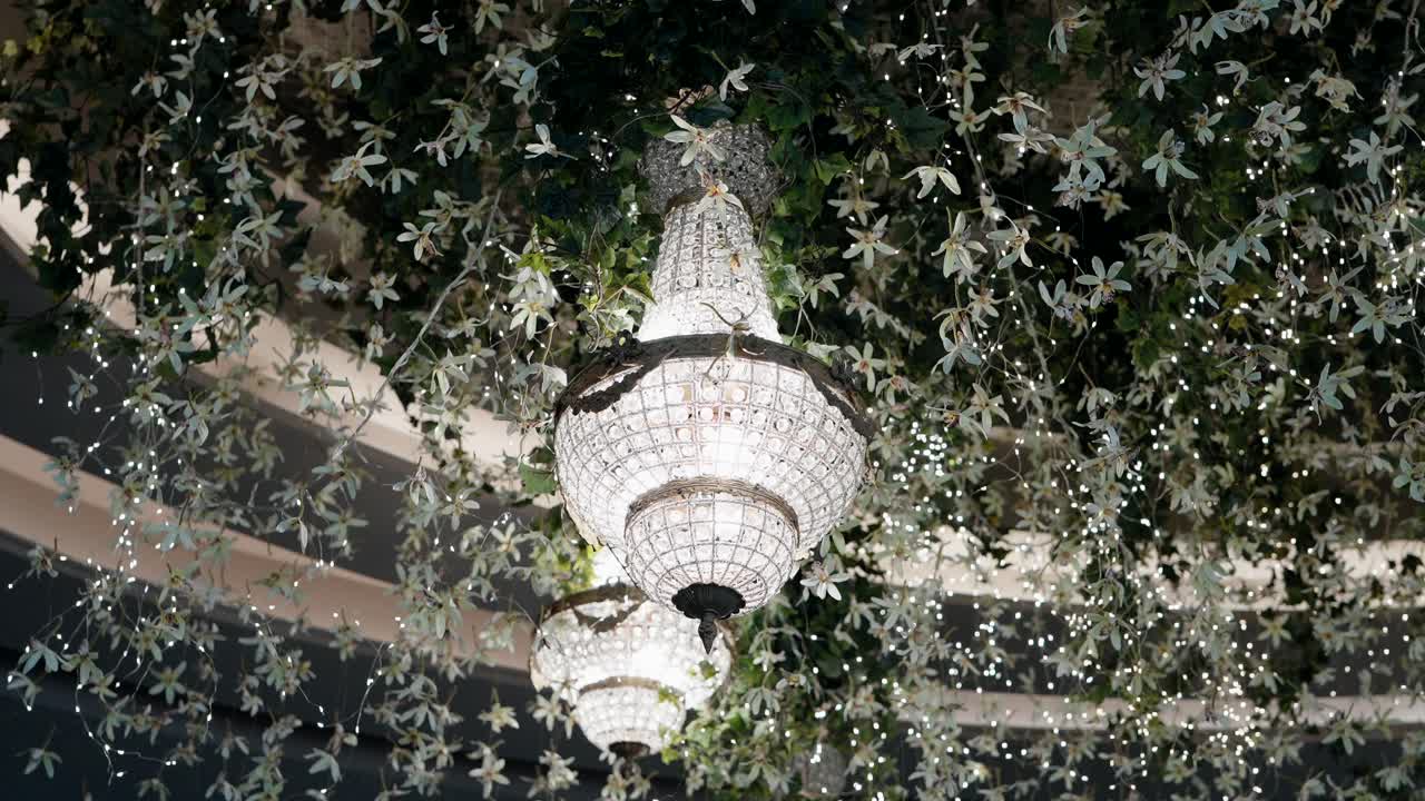 crystal chandeliers with floral ceiling and sparkling fairy lights at event venue