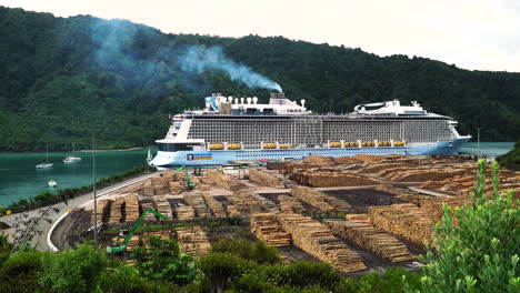 static view of cruise ship docked and large cargo of lumber on the quay