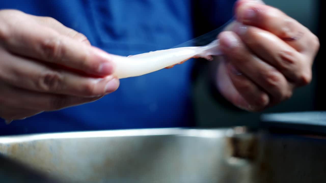 Close up and unique perspective of Chef's hands cleaning fresh squid under cinematic atmosphere.
