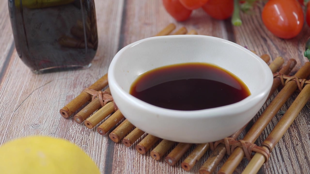 Темный соус в белой миске со свежими овощами и лимоном