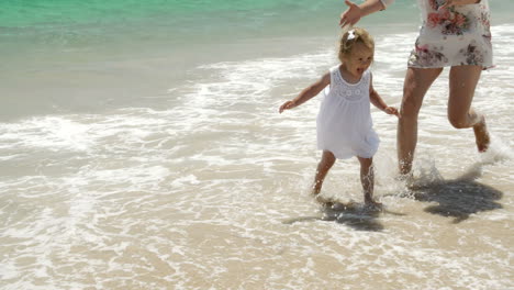 Little-girl-running-along-a-beach-with-her-mother