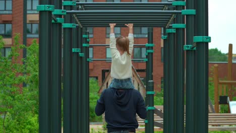 back view of father and little girl doing sports on sports ground outdoors. happy family, child and father play active game in summer park.