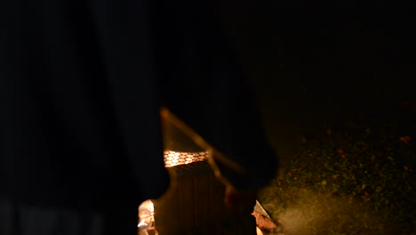 hombre colocando comida en una sartén sobre un pozo de fuego