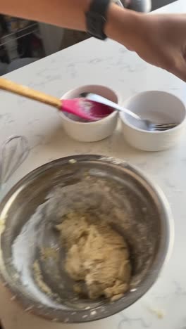 vertical video of rolling a vegan donut from a batter and adding to a pan to make vegan donuts