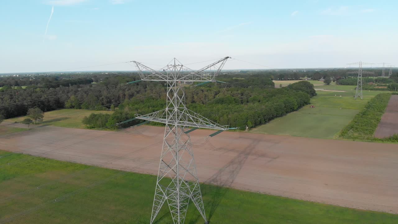 European countryside electricity transmission towers and power lines, blue sky aerial view