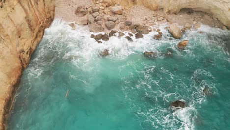 Fesselnde-Luftaufnahme-Aus-Der-Drohnenperspektive:-Versteckte-Türkisfarbene-Bucht,-Weiße-Wellen,-Die-Am-Strand-Krachen,-Hellbraune-Felsen-Vor-Der-Küste-Von-Gozo,-Meeresgischt-In-Bewegung