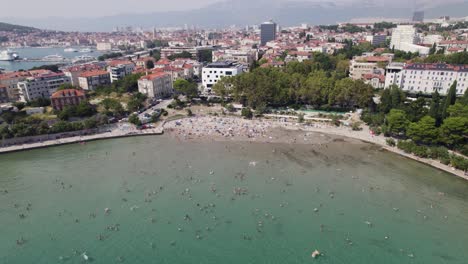 aerial: croatia, bacvice beach, split, with swimmers and cityscape backdrop