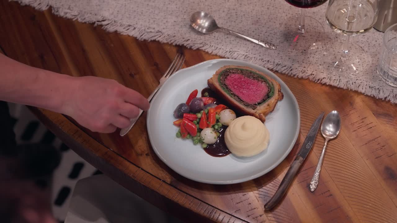 A rustic Beef Wellington dinner is presented at the table of a private dining experience (slow motion 4K)