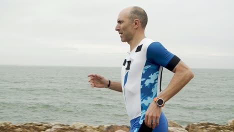 Concentrated-male-athlete-jogging-along-promenade