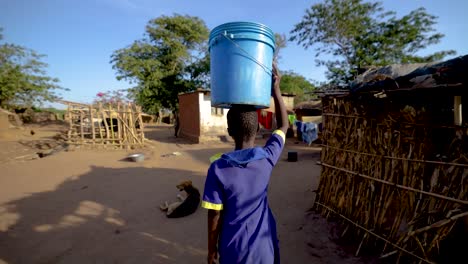 a girl getting water from a welling a village in malawi, africa. it was shot on an eos r. this shot she is carrying the water on her head.