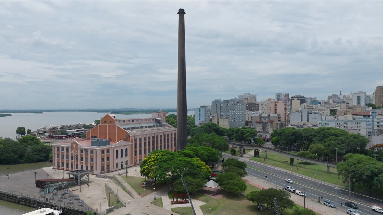 Usina do Gasometro dan tepi laut Porto Alegre yang diabadikan dalam tampilan orbit udara sinematik. Menampilkan lalu lintas perkotaan dan kaki langit di bawah langit mendung. Direkam dalam video profesional 4K D-Log 10-bit