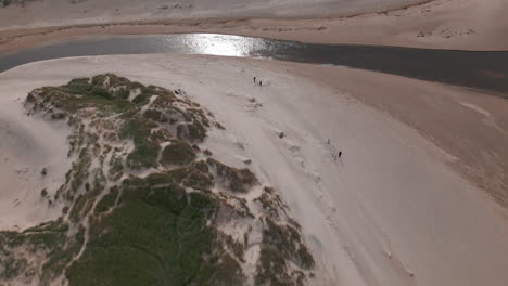 beachgoers stroll on sandy paths by denmark's dune-backed beach