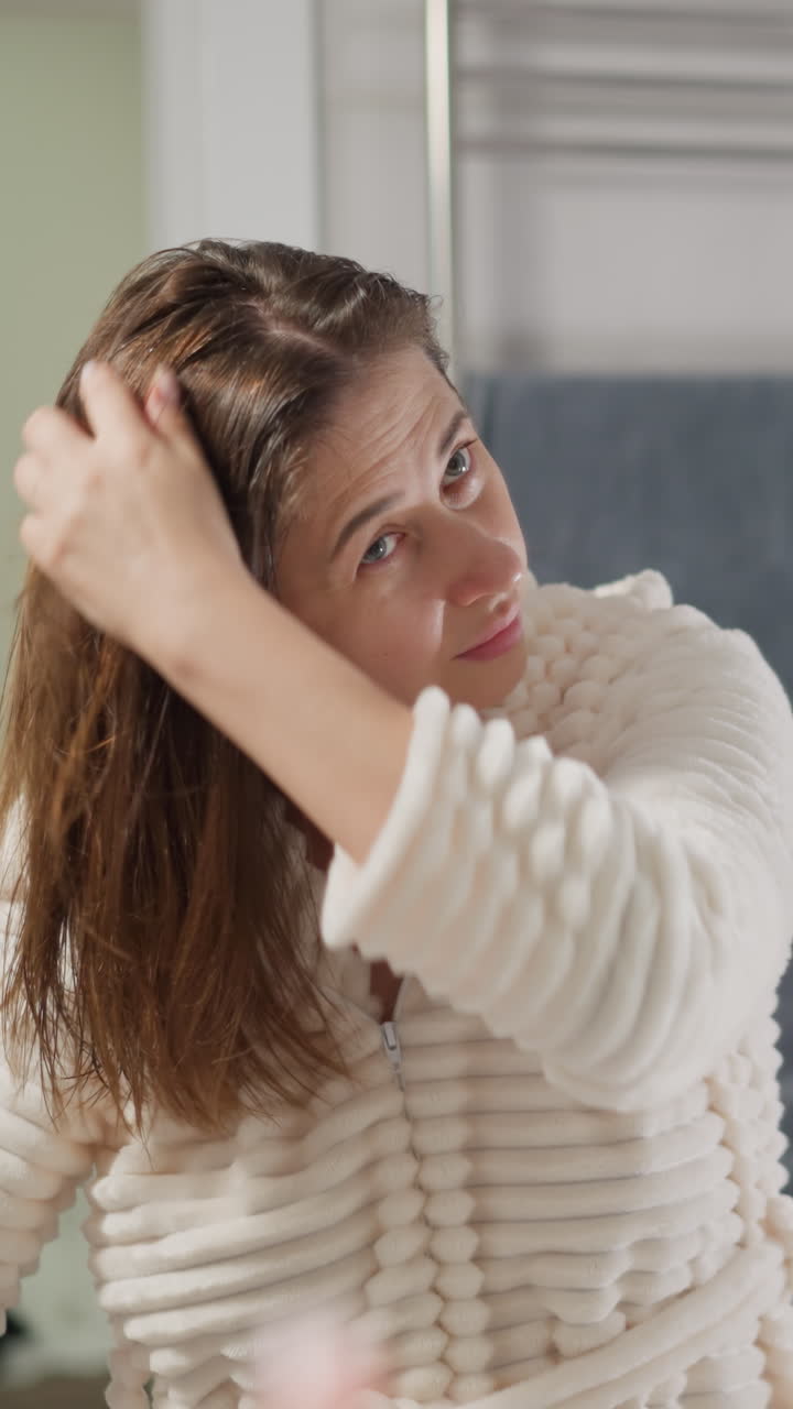 스파 살롱을 방문하는 여성은 머리카락을 각기 다른 방향으로 느린 동작으로 던집니다. 시트 같은 부서지기 쉬운 머리카락이있는 여자는 영양 기름으로 치료한 후 만족합니다.