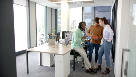 collaborating in modern office, diverse team discussing project using tablet and documents