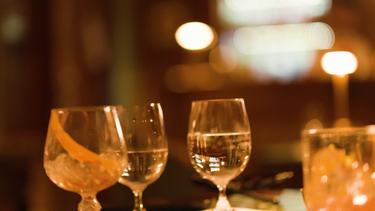 Warm ambient lighting highlights glassware and reflections on an elegant bar table, with soft bokeh
