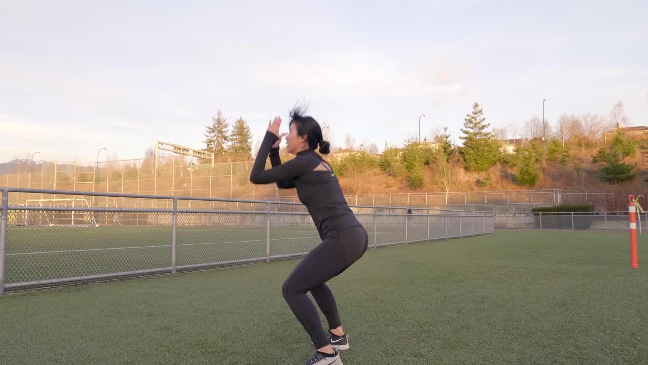 mujer asiática en ropa de entrenamiento haciendo saltos en cuclillas al aire libre