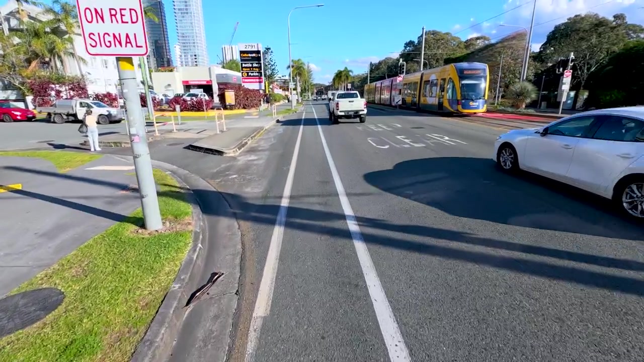 Stedelijk straatbeeld met lightrail en verkeer in Broadbeach.