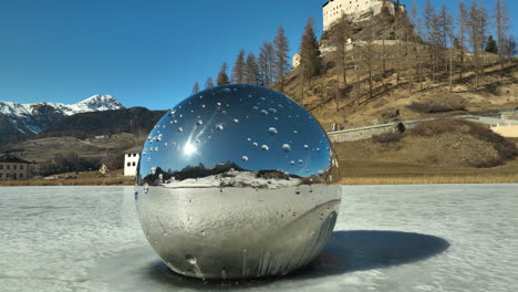 modern art mooring ball with in the background the historical schloss tarasp on a winter day