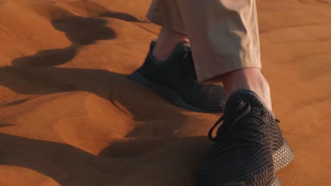 Man-Walking-On-Desert-Sand-With-Dune-Buggies-In-The-Back,-Low-Angle