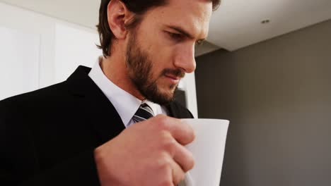 Businessman-reading-newspaper-while-having-coffee-in-kitchen