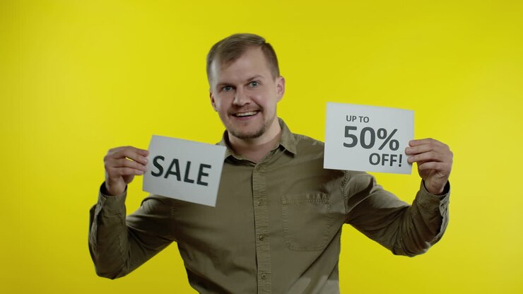 Uomo affascinante che mostra la scritta "Saldi" e l'indicazione "Fino al 50% di sconto". Concetto di Black Friday