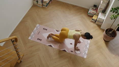 Mujer-Practicando-Ejercicios-De-Yoga-En-Un-Apartamento-Moderno,-Vista-De-Arriba-Hacia-Abajo-De-Una-Chica-En-Forma-Mientras-Hace-Ejercicio.