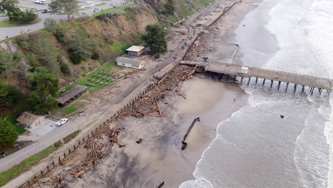 kłody zaśmiecające linię brzegową plaży stanowej seacliff po szalejącej burzy, która nawiedziła kalifornię w styczniu 2023 r., pozostawiając zniszczone molo i plażę