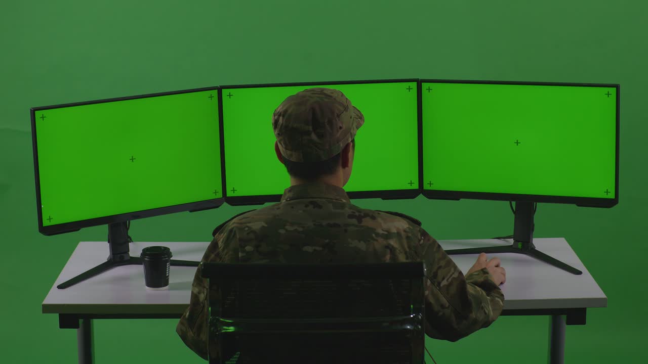 Vista Traseira de Homem Asiático, Soldado, Trabalhando com Mockup de Múltiplos Monitores de Computador em Estúdio de Tela Verde.