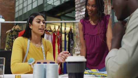 happy diverse fashion designers wearing the tape measures discussing work at office