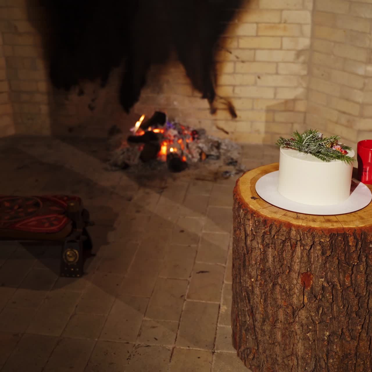 Comfortable interior in winter house. Mugs and festive cake on the background of fireplace. Cozy New Year mood.