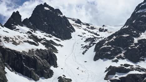 People-freeriding-down-rocky-slope-of-snowy-mountain