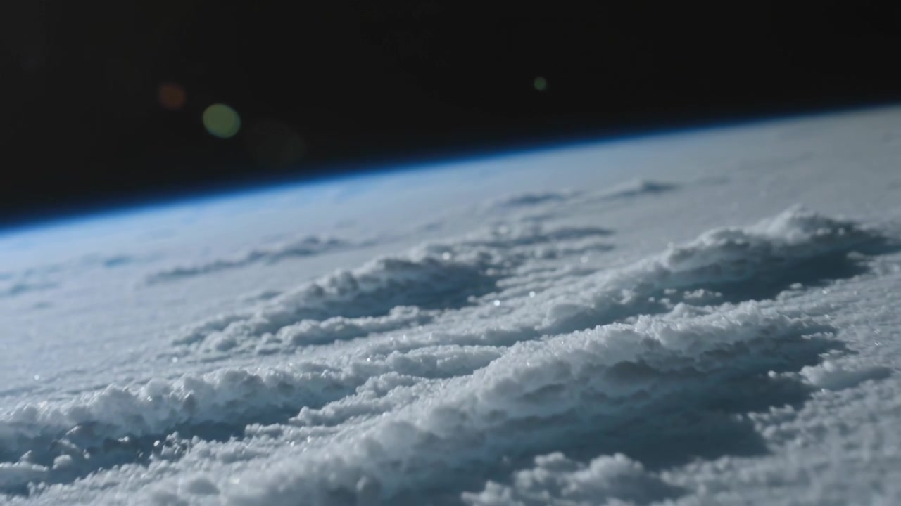 Orbiting camera tracking textured cloud deck under blue limb, revealing sun glints and lens flare