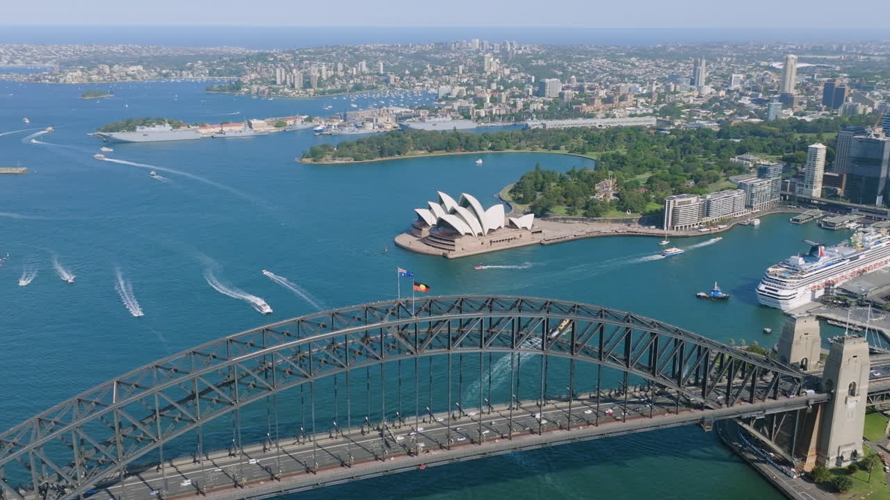 Aerial tracking shot of the Harbour bridge and the Opera House, in sunny Sydney
