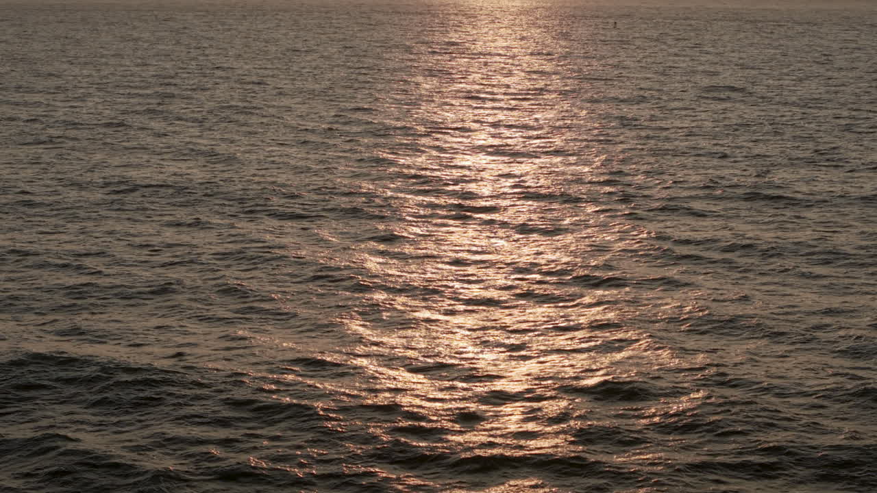 Ocean ripples background, drone shot at sunset flying low over the water.