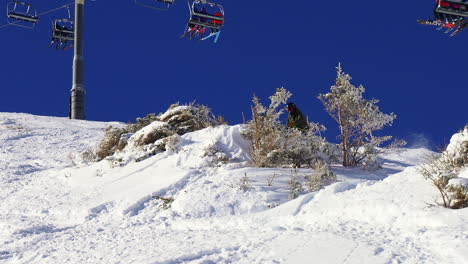 Skier-airs-and-grabs-skies-of-big-cliff-into-deep-fresh-powder-Telluride-ski-resort-crowd-watching-winter-Rocky-Mountains-Silverton-14er-Mt-Sneffels-Epic-Pass-Southern-Colorado-cinematic-follow