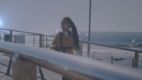 Animación-De-Puntos-De-Luz-Sobre-Una-Mujer-Birracial-Sonriente-Caminando-Con-Scooter-En-El-Paseo-Marítimo