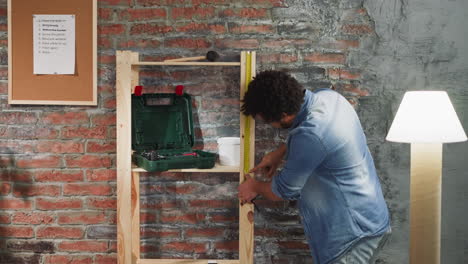 hombre negro mide la unidad de estanterías de madera con cinta de rodillo