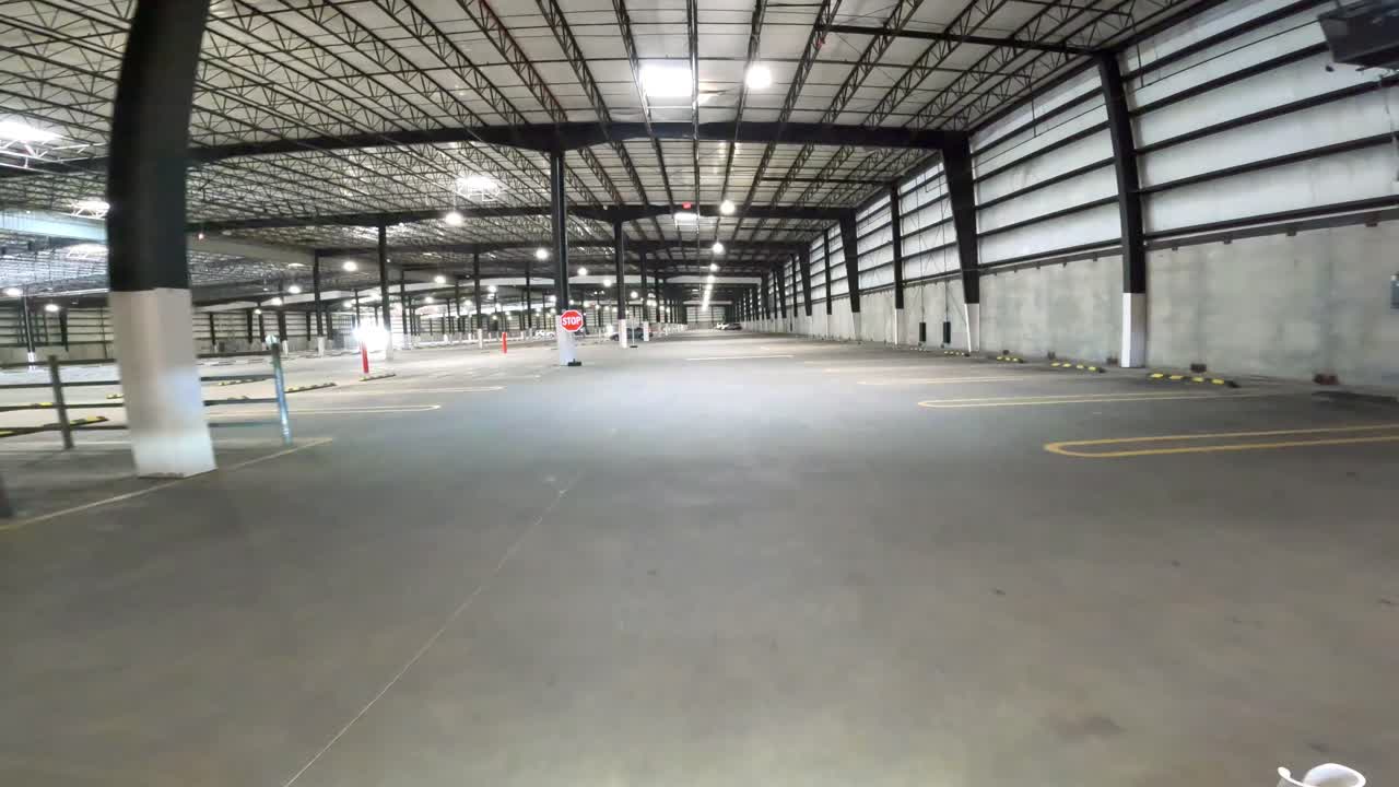 POV (punto di vista) di guida attraverso un parcheggio vuoto e recintato la mattina presto
